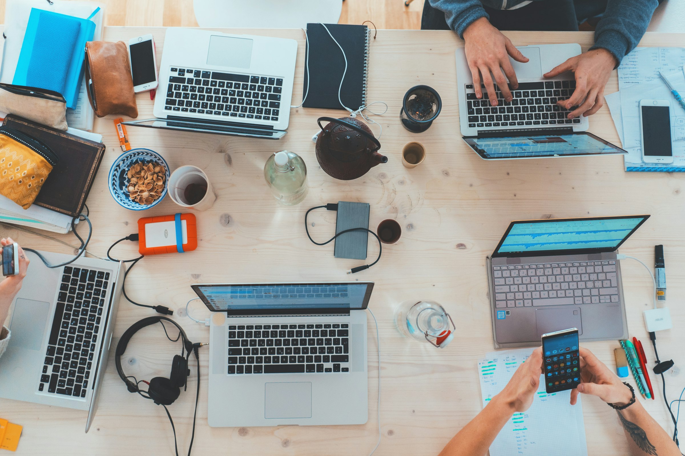 Colleagues working together on laptops around a shared desk, seen from above