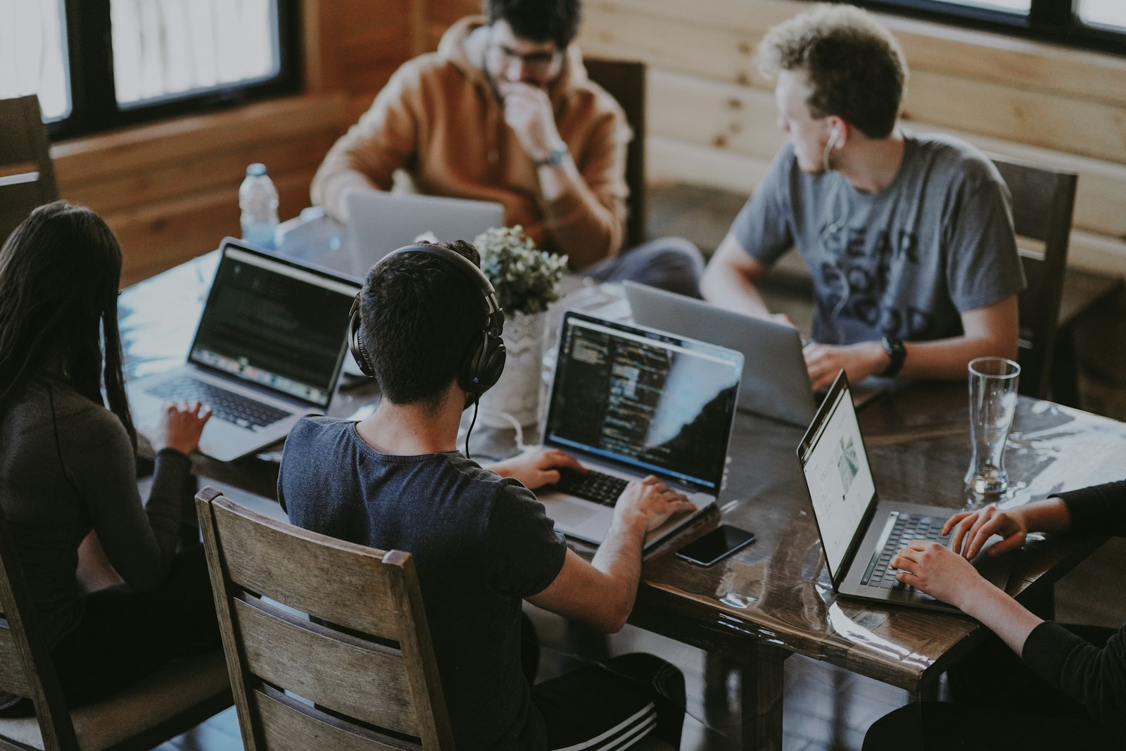 Five colleagues working on laptops around a wooden table